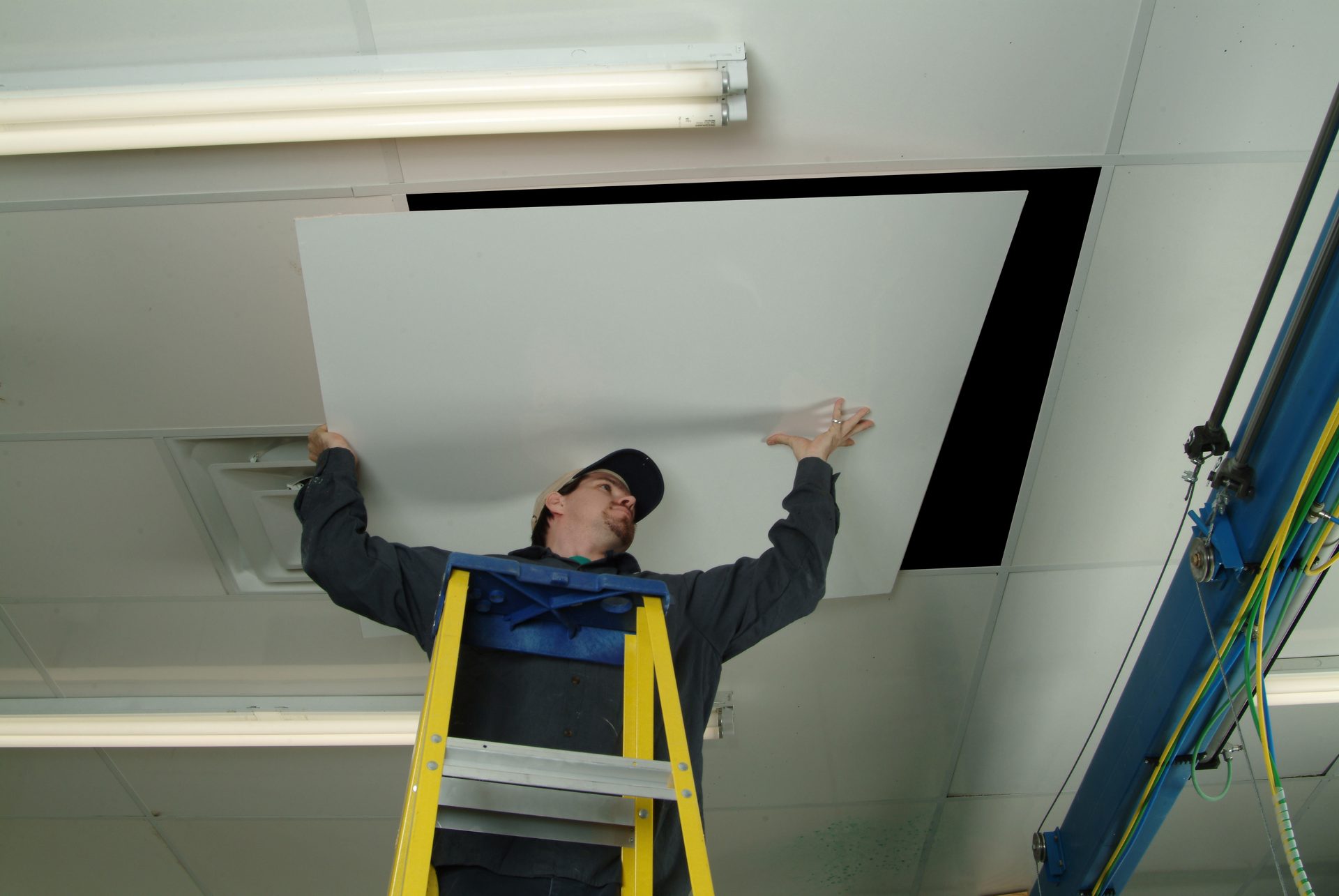 Installer fitting a fiberglass ceiling panel