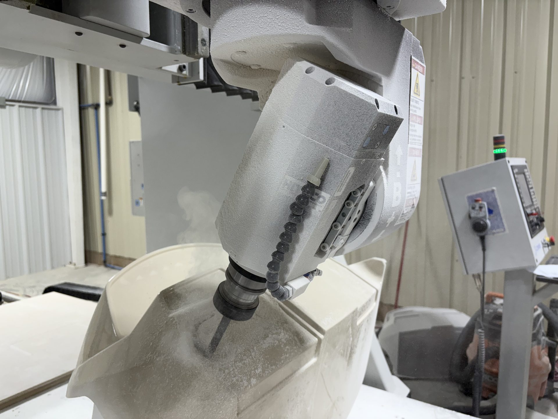Five-axis CNC head trimming a molded fiberglass part