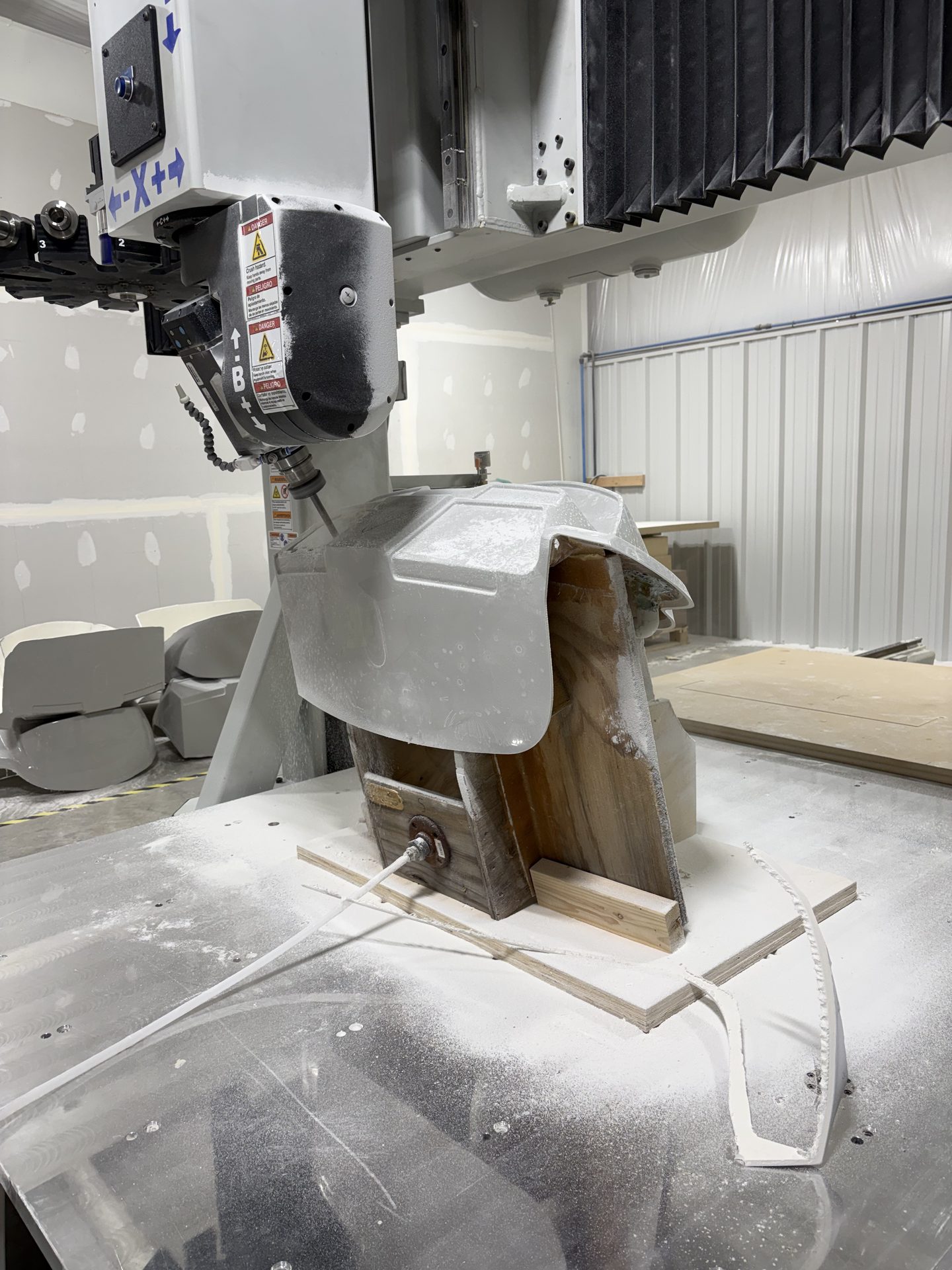 CNC trimming a gray fiberglass component