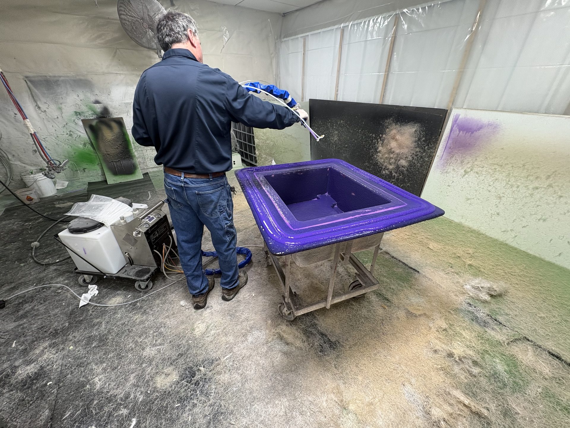 Technician spraying gelcoat into a purple mold