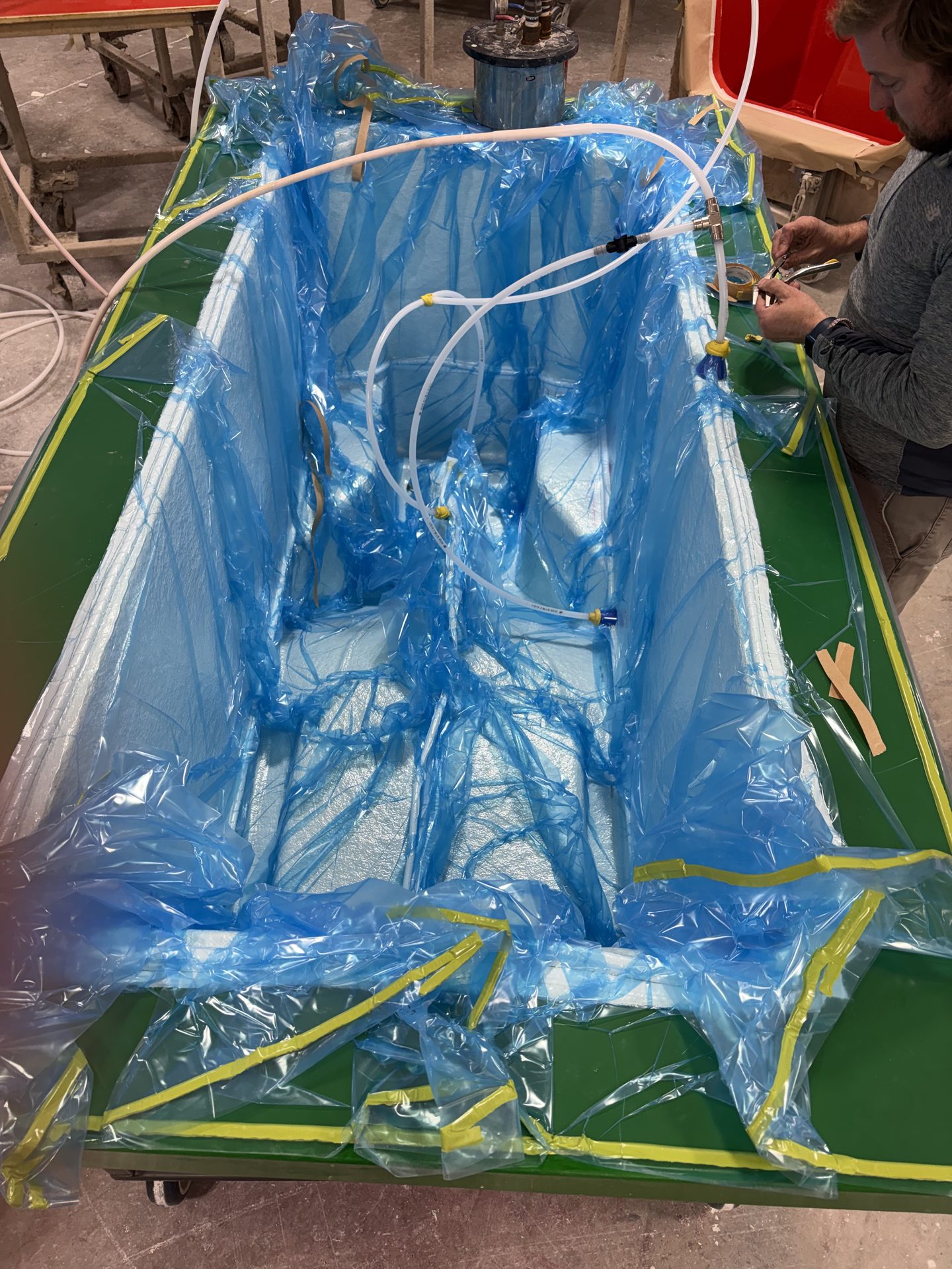 Vacuum infusion bag and feed lines over a hull mold