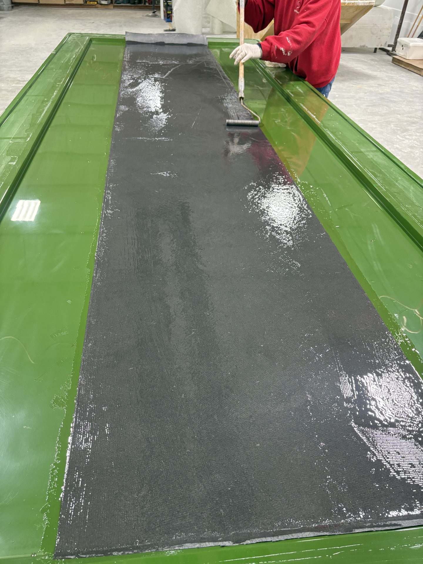 Technician wetting out reinforcement in a green mold